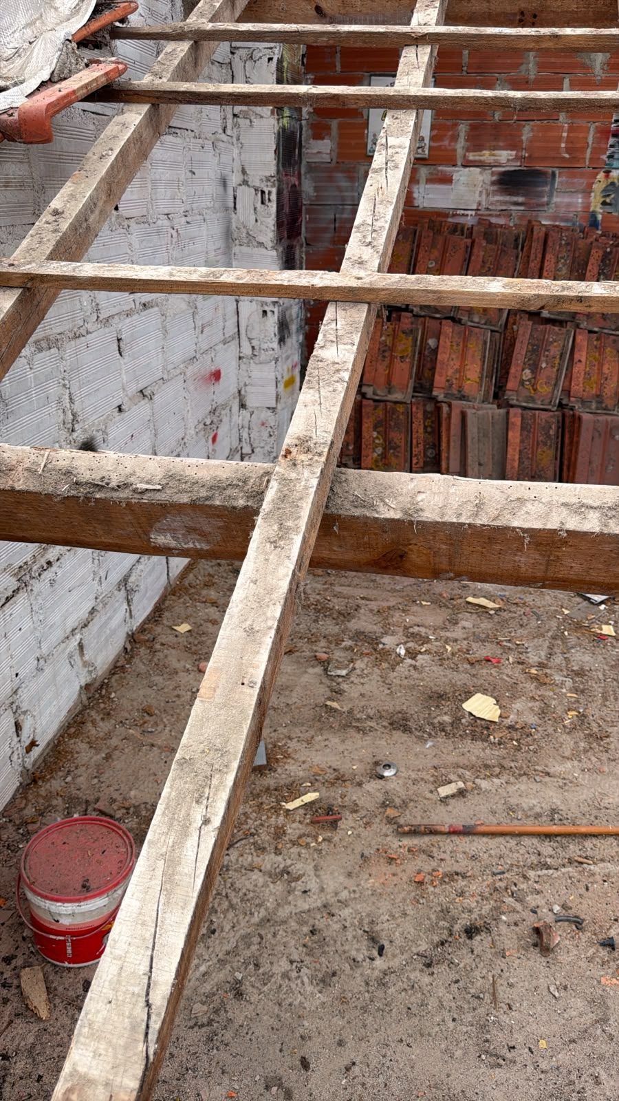 Estrutura de madeira de um telhado em obra, com telhas empilhadas